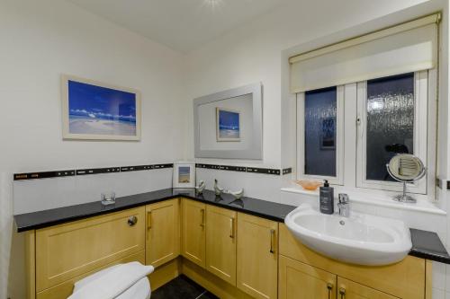 Un baño con lavabo e inodoro y dos ventanas. en Twin Palms No 2, en North Sunderland