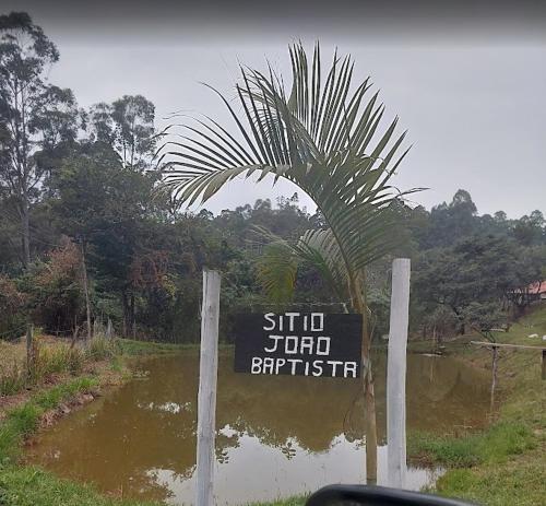a sign in front of a pond with a palm tree at Sitio João Baptista - ITU in Itu