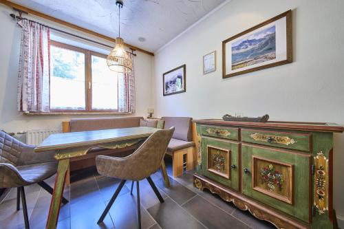 a dining room with a green dresser and a table and chairs at Apartments Enzian in Rauris