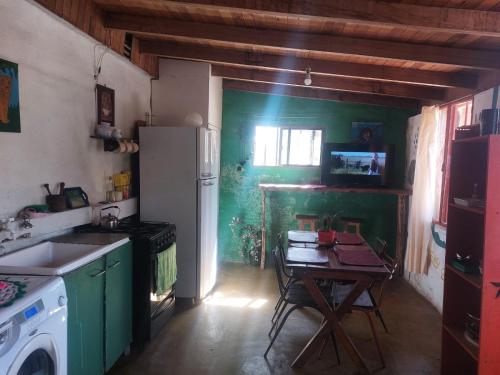 a kitchen with a table and a white refrigerator at Hostel Kuku in Mina Clavero