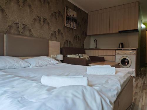 a large white bed in a room with a kitchen at Orbi Palace Delux A in Bakuriani