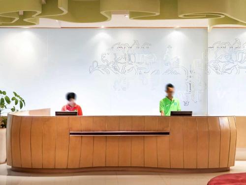 two people standing at a reception desk in a building at ibis Styles Yogyakarta in Yogyakarta