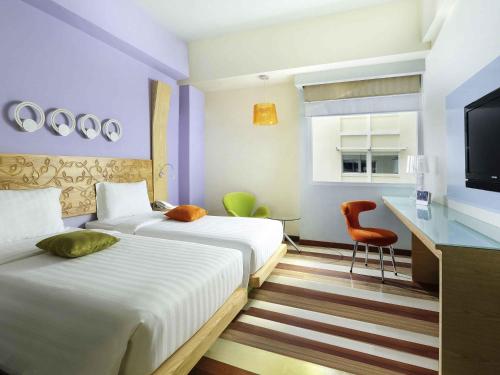 a hotel room with two beds and a television at ibis Styles Yogyakarta in Yogyakarta