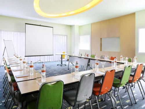 a conference room with tables and chairs and a projection screen at ibis Styles Yogyakarta in Yogyakarta