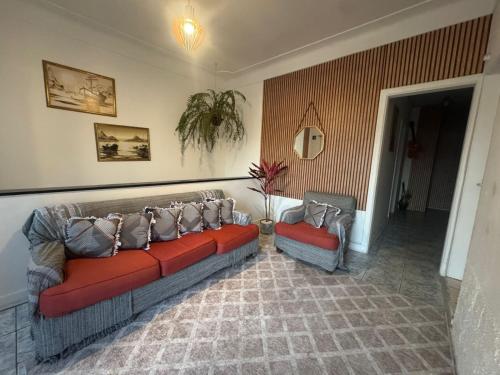 a living room with two red couches in a room at Pousada Mãe Linda in Aparecida
