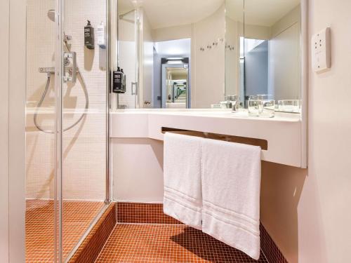 a bathroom with a shower and a sink with towels at ibis Styles London Southwark - near Borough Market in London