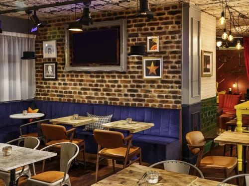 a dining room with tables and a tv on a brick wall at ibis Styles London Southwark - near Borough Market in London