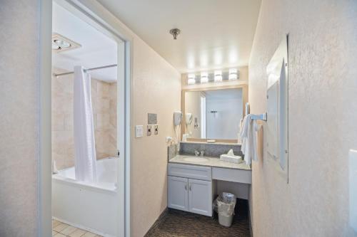a bathroom with a tub and a sink and a shower at Four Sails Resort in Virginia Beach