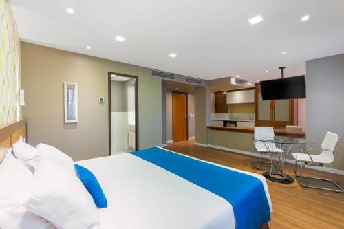 a hotel room with a large bed and a kitchen at Wyndham Sao Paulo Ibirapuera Convention Plaza in Sao Paulo