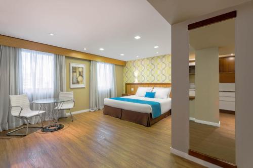 a bedroom with a bed and a table and chairs at Wyndham Sao Paulo Ibirapuera Convention Plaza in Sao Paulo