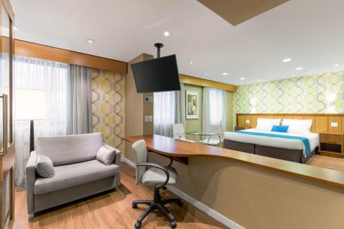 a hotel room with a bed and a desk and a bedroom at Wyndham Sao Paulo Ibirapuera Convention Plaza in Sao Paulo
