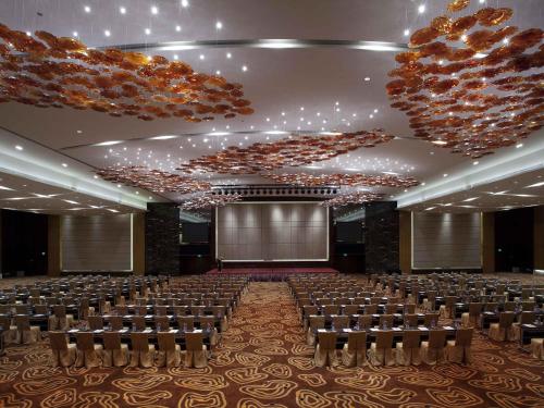 a large banquet hall with rows of chairs and a screen at Pullman Dongguan Changan in Dongguan