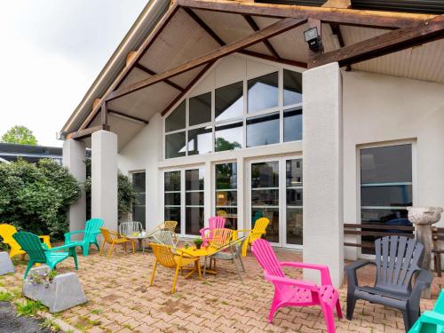 un grupo de sillas y mesas coloridas en un patio en ibis Styles Brive Ouest, en Brive-la-Gaillarde