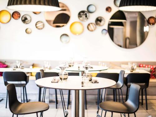 a restaurant with white tables and chairs and mirrors at ibis Styles Toulouse Cite Espace in Toulouse