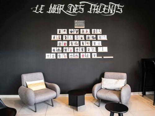 two chairs in a waiting room with a wall at ibis Styles Toulouse Cite Espace in Toulouse