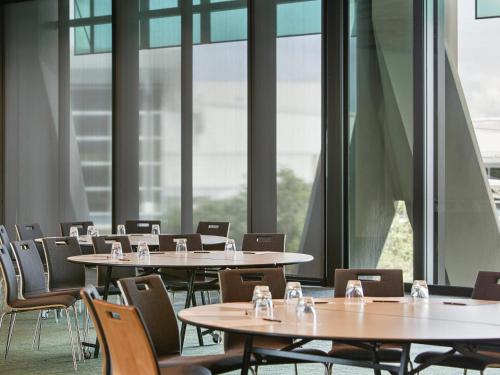 a row of tables and chairs in a room with windows at Novotel Auckland Airport in Auckland