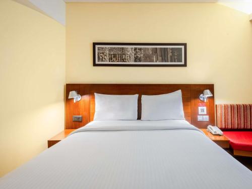 a bedroom with a large bed and a red chair at ibis New Delhi Aerocity - An Accor Brand in New Delhi