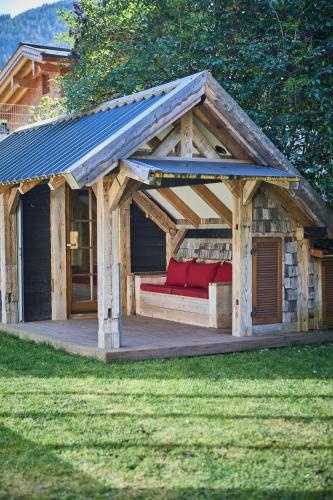 a wooden pavilion with a red couch on a deck at Apartments Enzian in Rauris