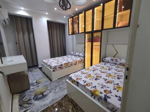 a bedroom with two beds and a mirror at شقة مميزة بجوار كورنيش النيل اسوان - عائلات فقط in Aswan