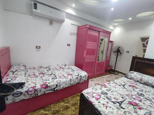 a bedroom with two beds and a pink cabinet at شقة مميزة بجوار كورنيش النيل اسوان - عائلات فقط in Aswan