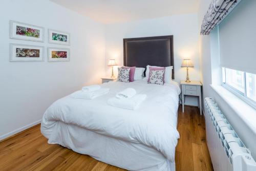 Un dormitorio con una gran cama blanca con dos almohadas. en South Lodge West, en Holkham