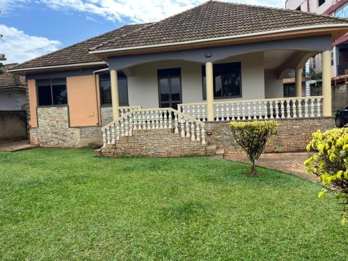 a house with a porch and a yard with green grass at Paradise in najjera in Kampala