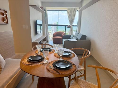 a table with plates and glasses on it in a living room at Studio Design 3 Apt 801 -Mandi Hospitalidade in Maceió