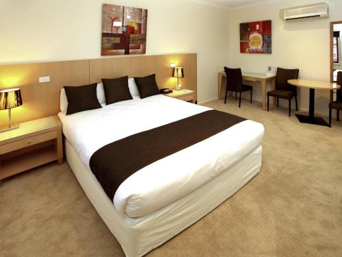 ミルデューラにあるMercure Hotel Milduraのベッドルーム(大型ベッド1台、テーブル、椅子付)