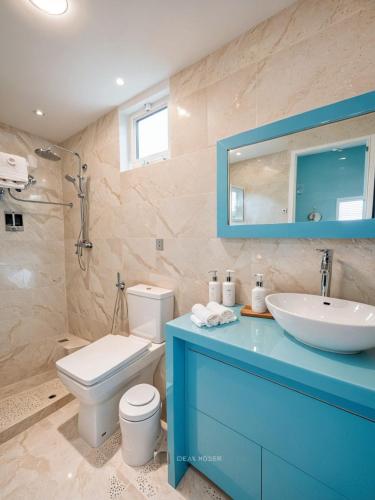 a bathroom with a sink and a toilet and a mirror at SunSeaSurf Maldives in Thulusdhoo