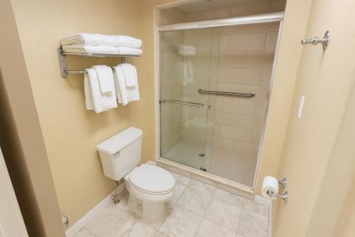 a bathroom with a toilet and a shower with towels at Four Sails Resort in Virginia Beach