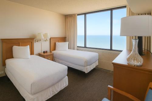 a hotel room with two beds and a large window at Four Sails Resort in Virginia Beach