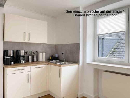 a kitchen with white cabinets and a window at Schöne Apartments I private Parkplätze I home2share in Münster