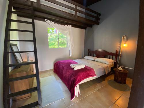 a bedroom with a bed with a purple blanket at Casa Reserva Encantada in Garopaba