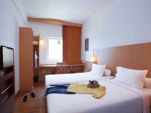a hotel room with two beds and a television at Ibis Bali Kuta in Kuta