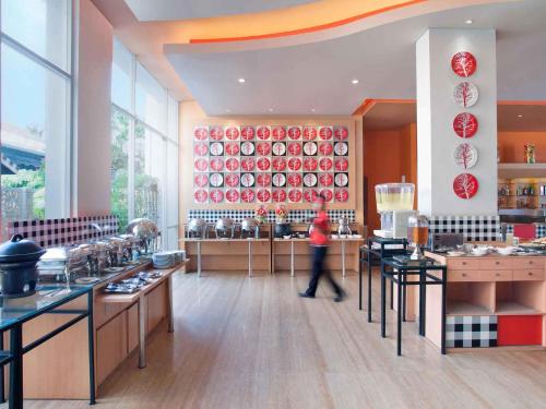a person walking through a kitchen with red plates on the wall at Ibis Bali Kuta in Kuta