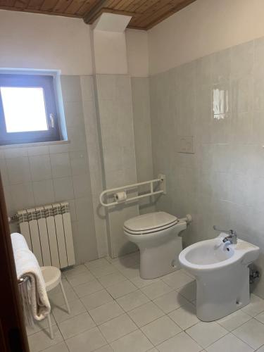 a white bathroom with a toilet and a sink at Albergo il Pescatore in Villetta Barrea