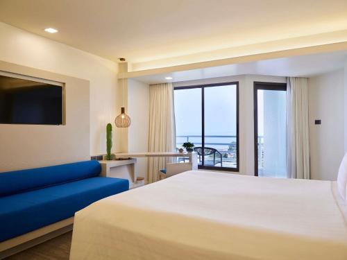 a bedroom with a large bed and a blue couch at Pullman Pattaya Hotel G in Pattaya North