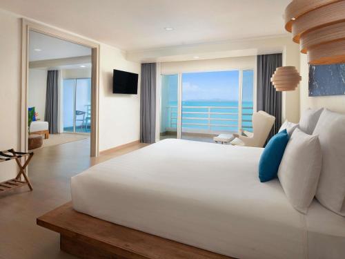 a bedroom with a large bed with a view of the ocean at Pullman Pattaya Hotel G in Pattaya North