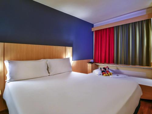 a large white bed in a room with a red window at ibis Rio de Janeiro Botafogo in Rio de Janeiro