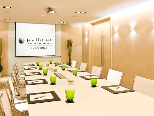 a conference room with a long table with chairs and a screen at Pullman Pattaya Hotel G in Pattaya North