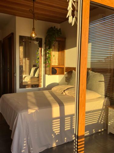 a bedroom with a large white bed with a mirror at SOL DA LAGOA - PRAIA DO ROSA in Praia do Rosa
