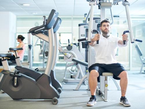 a man sitting in a gym on a gym machine at Mercure Newcastle George Washington Hotel Golf & Spa in Newcastle upon Tyne