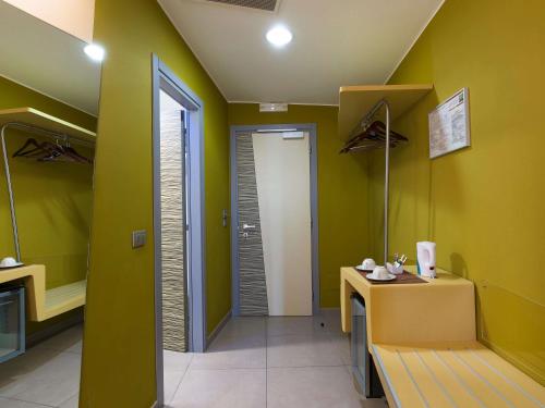 a bathroom with green walls and a table with a mirror at ibis Styles Catania Acireale in Acireale