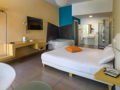 a bedroom with a large bed and a bathroom at ibis Styles Catania Acireale in Acireale