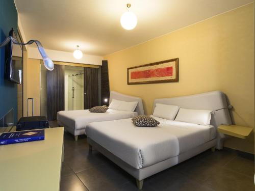 a hotel room with two beds and a table at ibis Styles Catania Acireale in Acireale