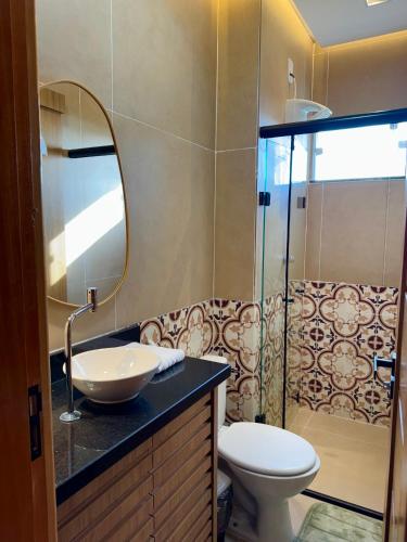 a bathroom with a sink and a toilet and a mirror at Ilha Bela Alter do chão - Apartment 2 suites in Santarém