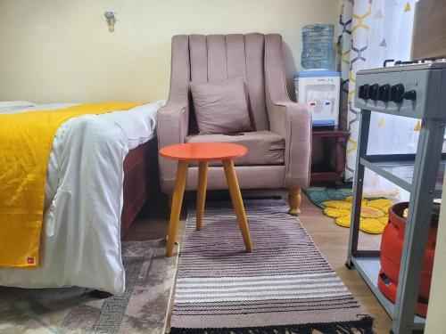 a chair and a table in a bedroom at Blissful Suite, Studio BNB at Kamakis, Ruiru- in Ruiru