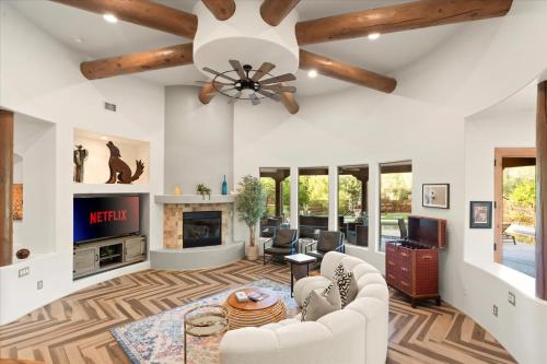 a living room with a ceiling fan and a fireplace at Mountain Views - Pool - Games - YogaDeck in Carefree
