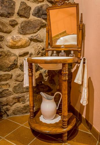 a mirror and a vase on a stand with a table at Casa de piedra en el corazón de Potes in Potes