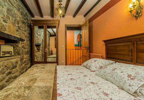 a bedroom with a bed and a stone wall at Casa de piedra en el corazón de Potes in Potes